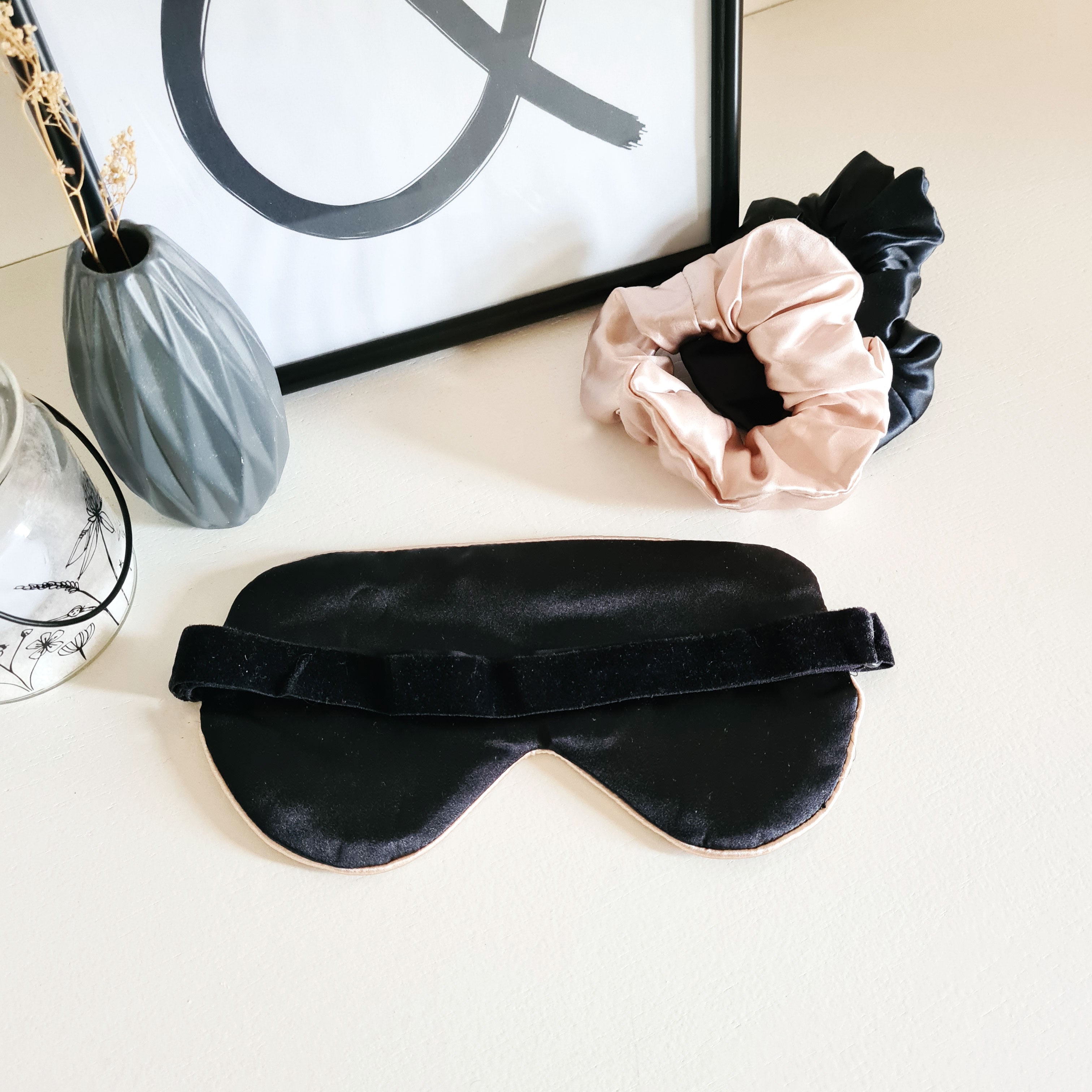 Black silk sleep mask with caramel-colored trim and elastic band